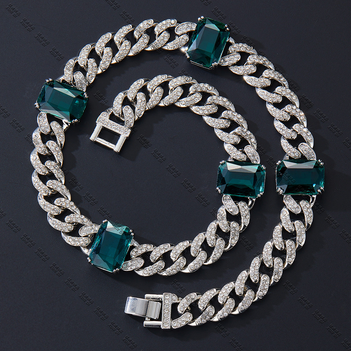 Silver chain bracelet with green gemstones on a dark background