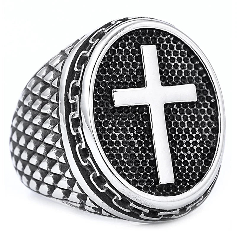 Silver ring with a textured band and central cross design on a white background