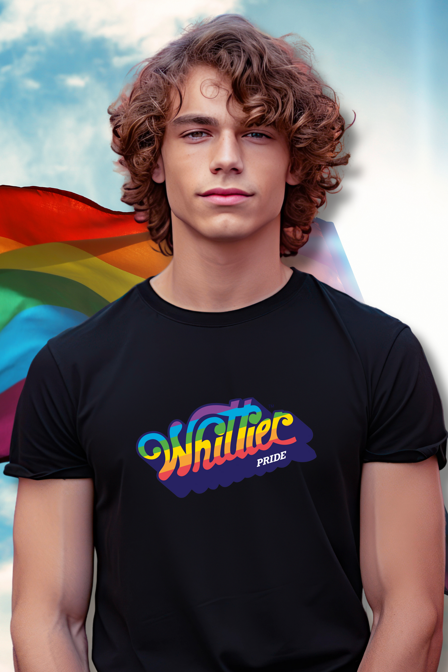 Person wearing a black t-shirt with colorful text, standing in front of a rainbow flag.