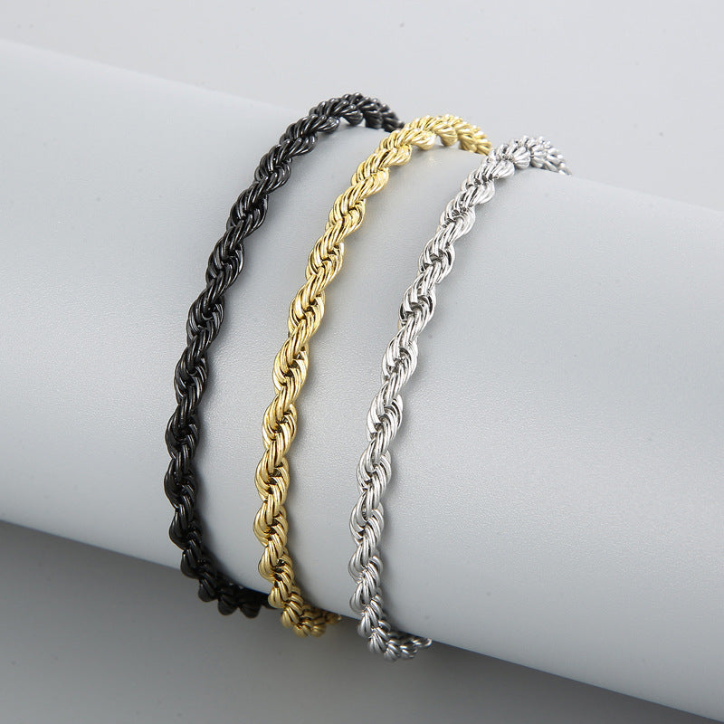 Three braided bracelet in black, gold, and silver on a white surface.