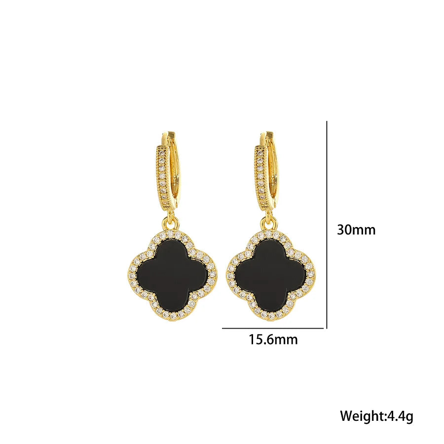 Gold earrings with black clover-shaped stones and measurements on a white background