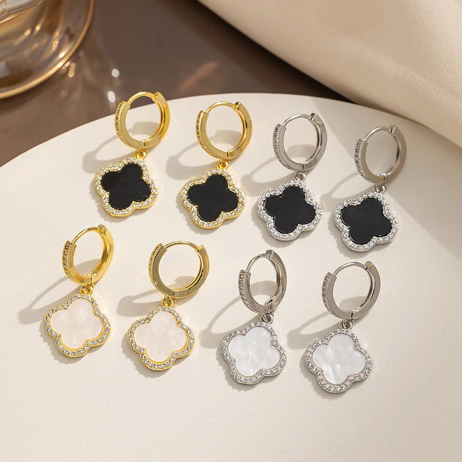 Set of gold and silver earrings with black and white stones on a beige surface