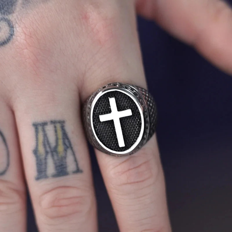Ring with a cross design on a finger with tattoos