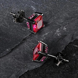 Red gemstone stud earrings on a dark stone surface