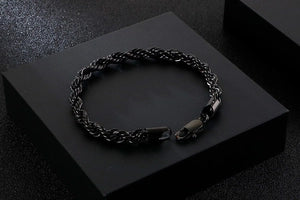 Black braided bracelet on a black surface with a dark background