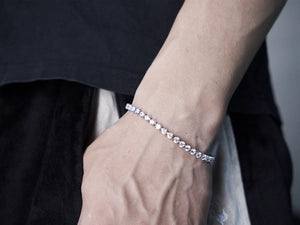 Silver bracelet on a wrist with a neutral background