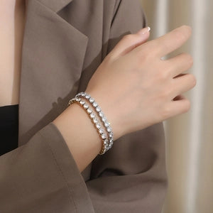 Close-up of a hand wearing a silver bracelet with a neutral background