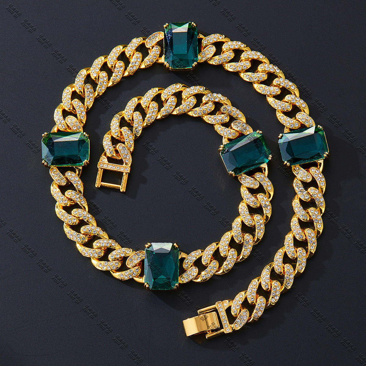 Gold chain bracelet with green gemstones on a dark background