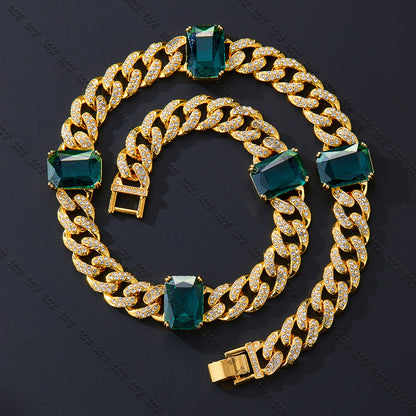 Gold chain bracelet with green gemstones on a dark background