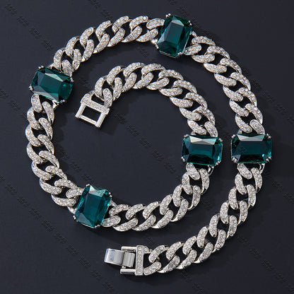 Silver chain bracelet with green gemstones on a dark background