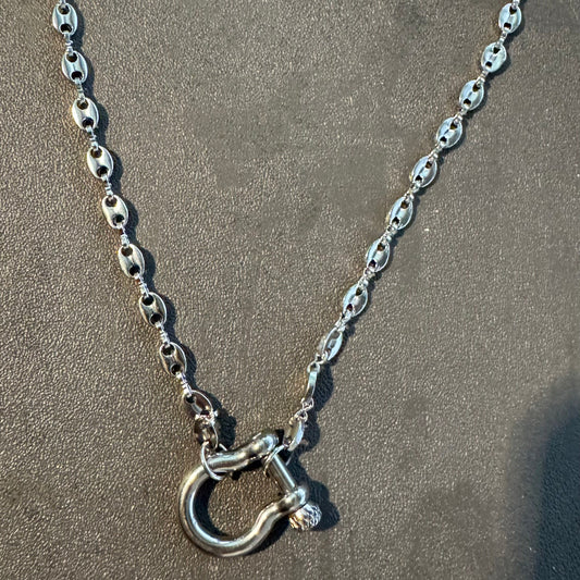 Silver chain necklace with a clasp on a sandy surface