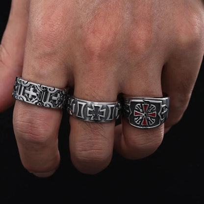 Three metallic rings with intricate designs on a person's hand against a dark background
