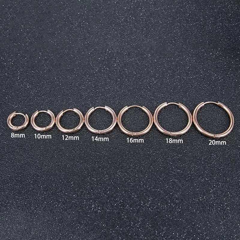 Set of rose gold hoop earrings in various sizes on a dark textured background