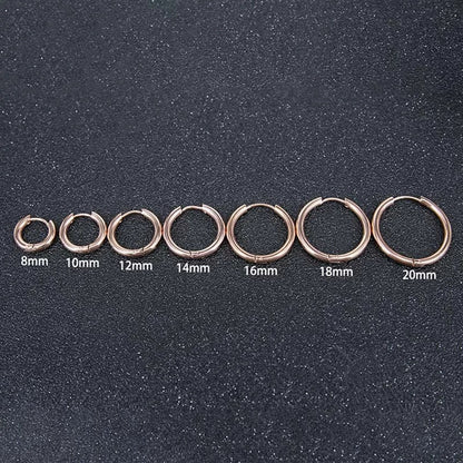 Set of rose gold hoop earrings in various sizes on a dark textured background