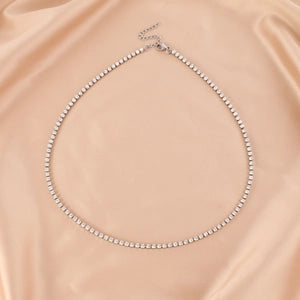 Silver beaded necklace on a beige fabric background