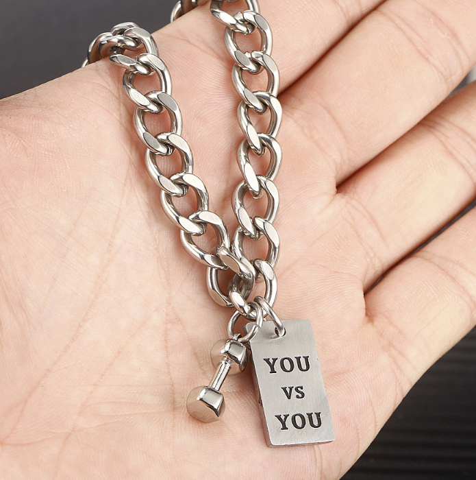 Silver chain bracelet with 'YOU VS YOU' tag on a hand