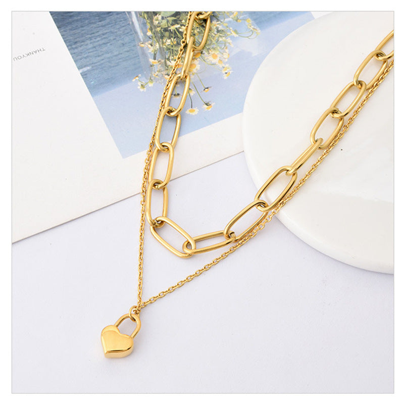 Gold chain necklace with a heart lock pendant on a light background