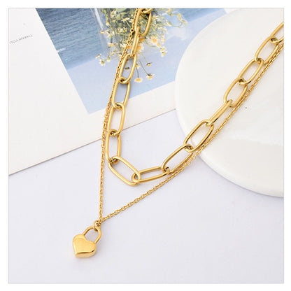 Gold chain necklace with a heart lock pendant on a light background