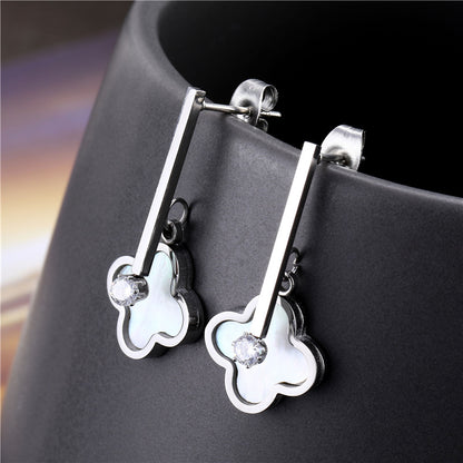 Silver earrings with clover-shaped drops on a dark surface