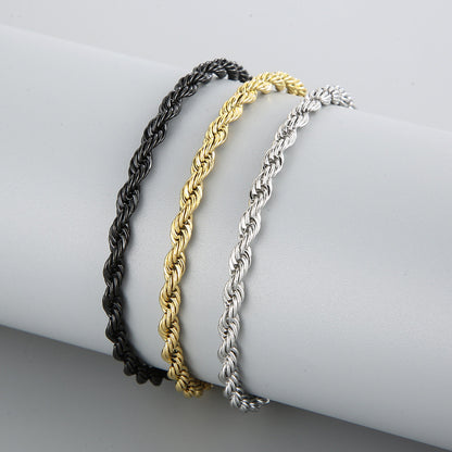 Three braided bracelet in black, gold, and silver on a white surface.