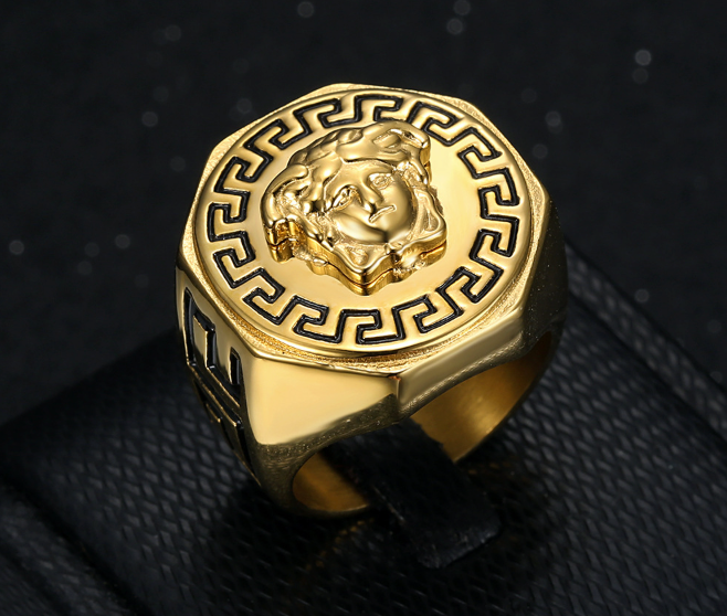 Gold ring with intricate design on a black textured background