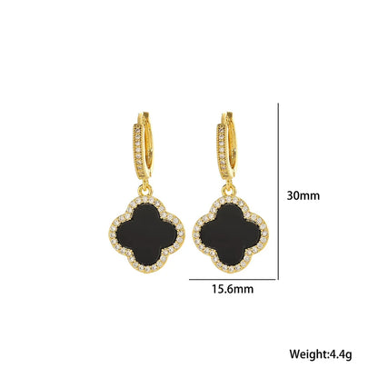 Gold earrings with black clover-shaped stones and measurements on a white background