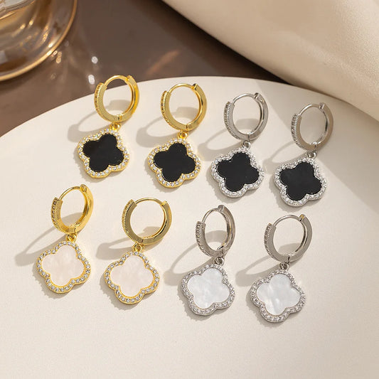 Set of gold and silver earrings with black and white stones on a beige surface