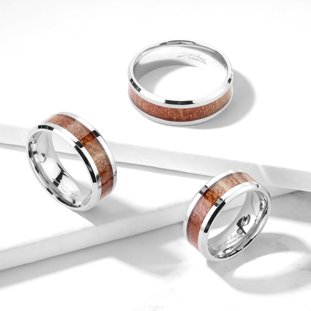 Three stainless steel rings with wood inlay centers, displayed on a white surface.