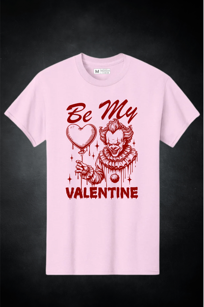 Pink t-shirt with a graphic design of a clown holding a heart and text 'Be My Valentine' on a dark background.