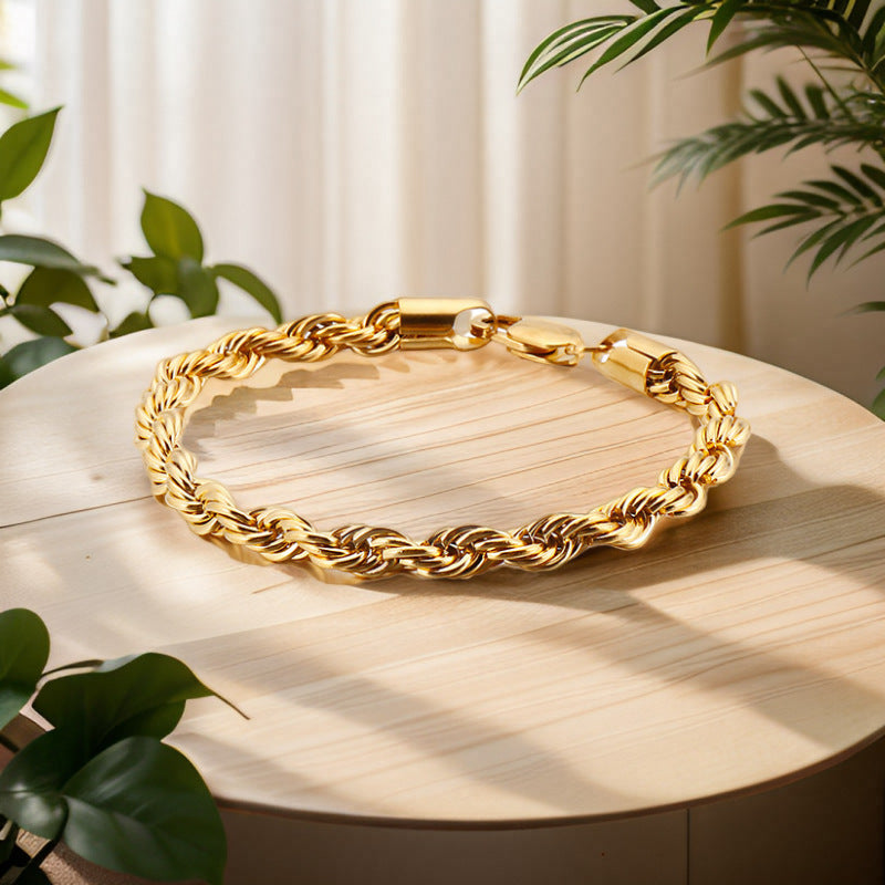 Gold chain necklace on a wooden surface with plants in the background