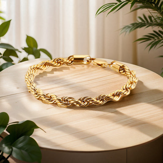 Gold chain necklace on a wooden surface with plants in the background