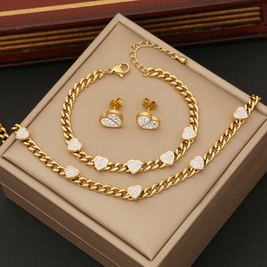 Gold jewelry set with heart-shaped stones on a beige box