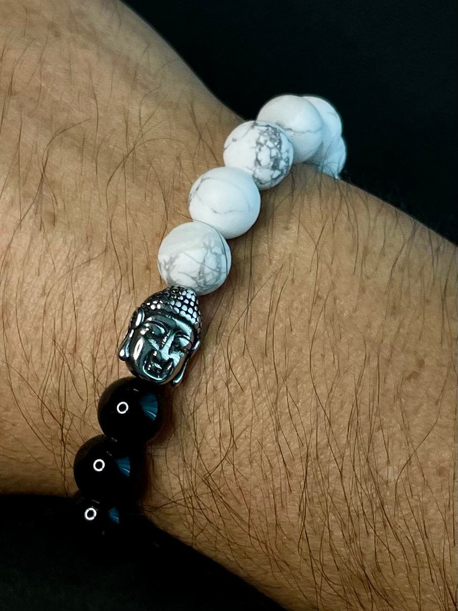 Handcrafted black and white beaded bracelet featuring glossy black stones, matte white howlite beads, silver Buddha head, cross charm and protective Hamsa hand.